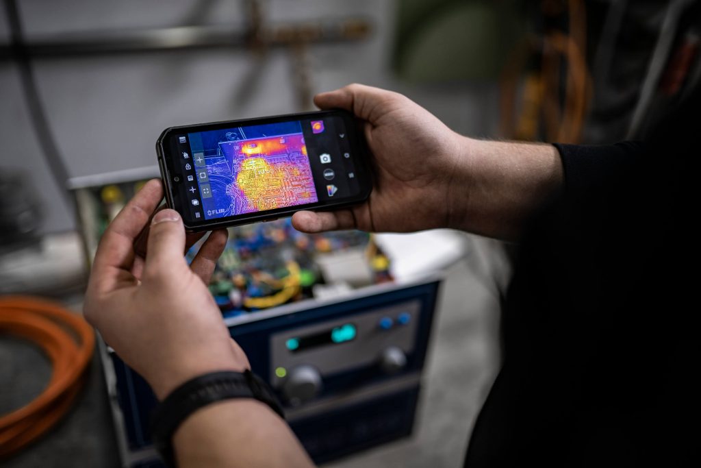 Service-Mitarbeiter mit Handy, das die Analyse der Umrichterfunktion zeigt